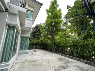 Spacious outdoor patio with lush greenery and modern house exterior