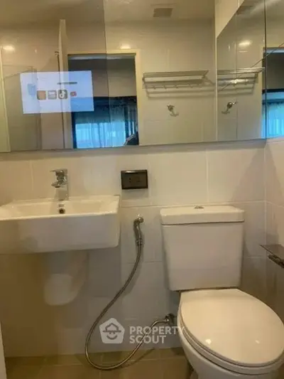 Compact bathroom with modern fixtures and wall-mounted sink in a cozy apartment.