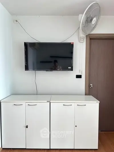 Modern living room with wall-mounted TV and sleek white cabinets