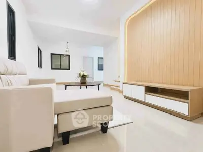 Spacious modern living room with elegant beige sofa and stylish wooden paneling.