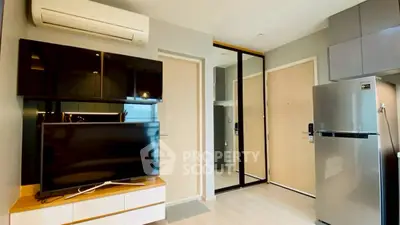 Modern apartment interior with sleek TV setup and stainless steel fridge, showcasing contemporary living space.