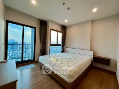 Spacious bedroom with city view and large windows in modern apartment.