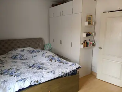 Cozy bedroom with floral bedding and ample storage in a modern apartment.