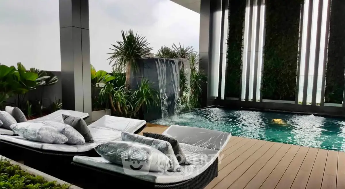 Luxurious rooftop pool with waterfall feature and stylish lounge chairs, perfect for relaxation and entertainment.