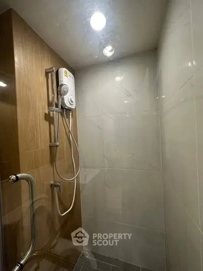 Modern bathroom with sleek shower and water heater in a contemporary real estate property.