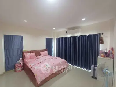 Spacious bedroom with pink bedding and modern decor, featuring air conditioning and ample natural light.