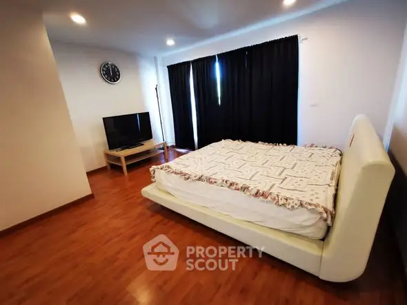 Spacious bedroom with wooden flooring and modern decor