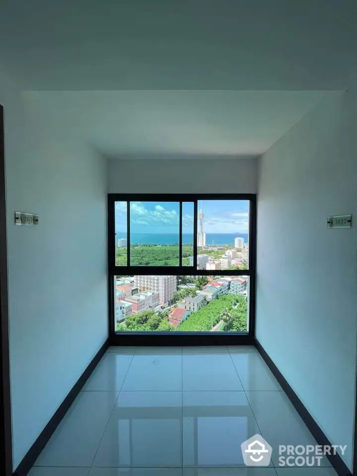 Stunning high-rise view of cityscape and ocean from modern apartment window.