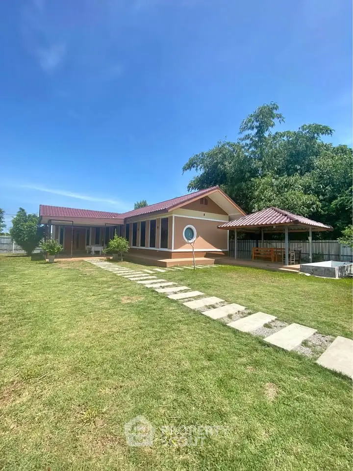 Charming single-story home with spacious garden and inviting pathway under clear blue skies.