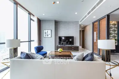 Luxurious living room with modern decor, floor-to-ceiling windows offering ample natural light, and elegant furnishings.