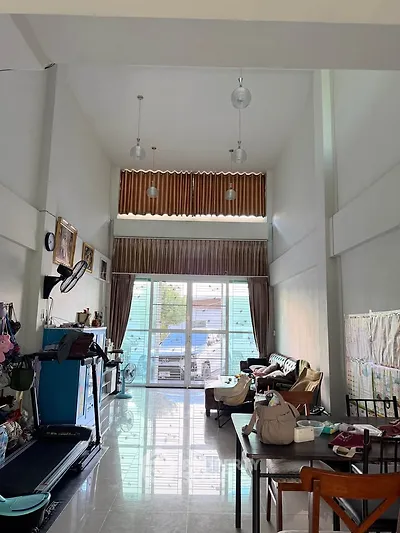 Spacious living room with high ceilings and modern decor, featuring large windows for natural light.