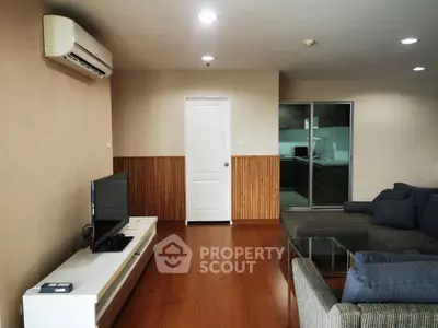 Spacious living room with modern furniture and air conditioning, adjacent to a sleek kitchen.