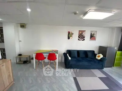 Modern living room with stylish decor and vibrant furniture, featuring a cozy sofa and sleek mini fridge.