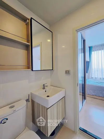 Modern bathroom with sleek fixtures and view into a cozy bedroom