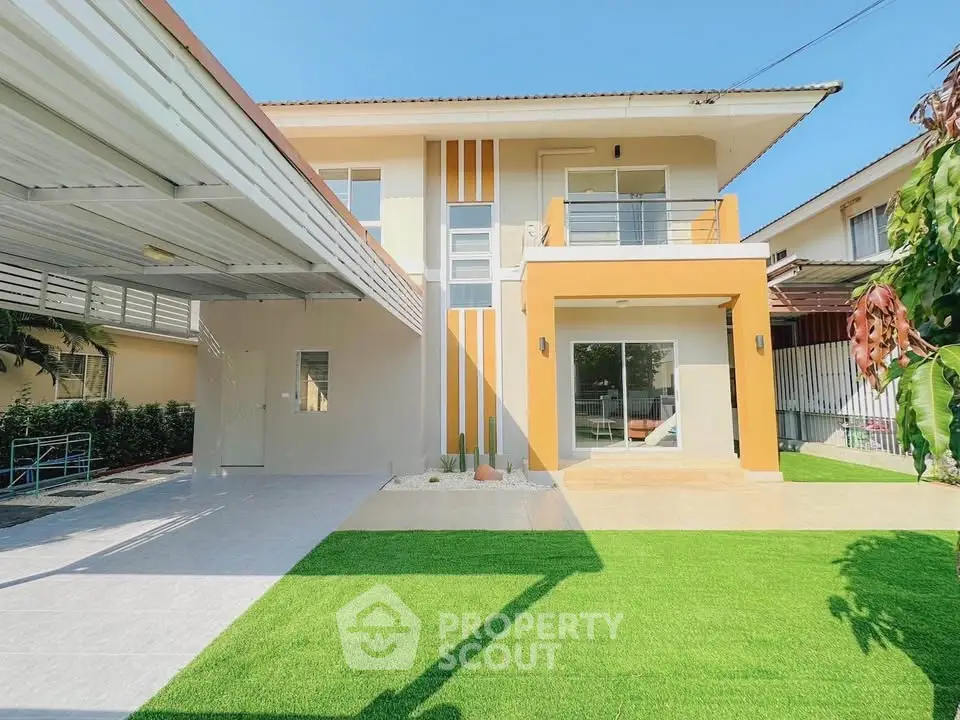 Modern two-story house with balcony and spacious green lawn in sunny setting.