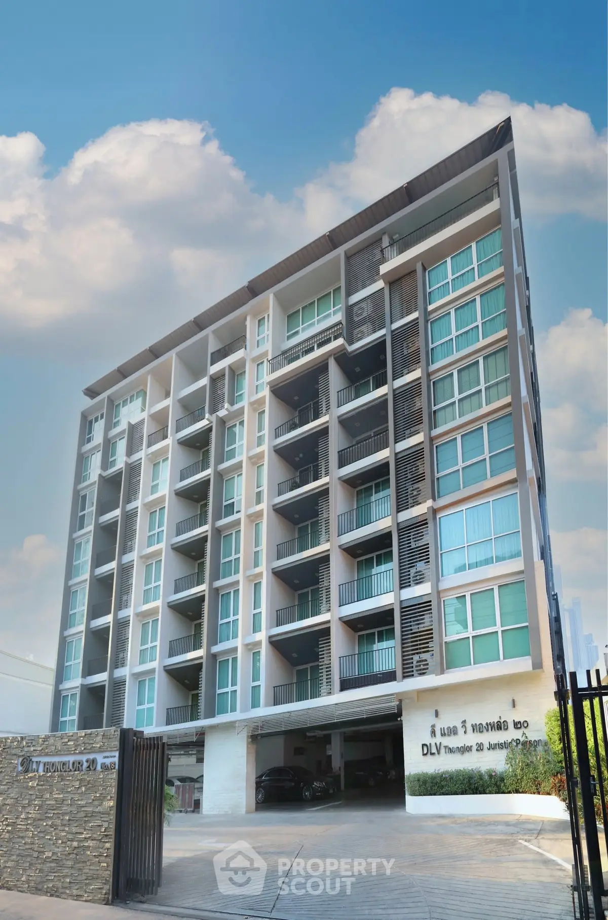 Modern multi-story residential building with balconies and parking area, showcasing urban living.