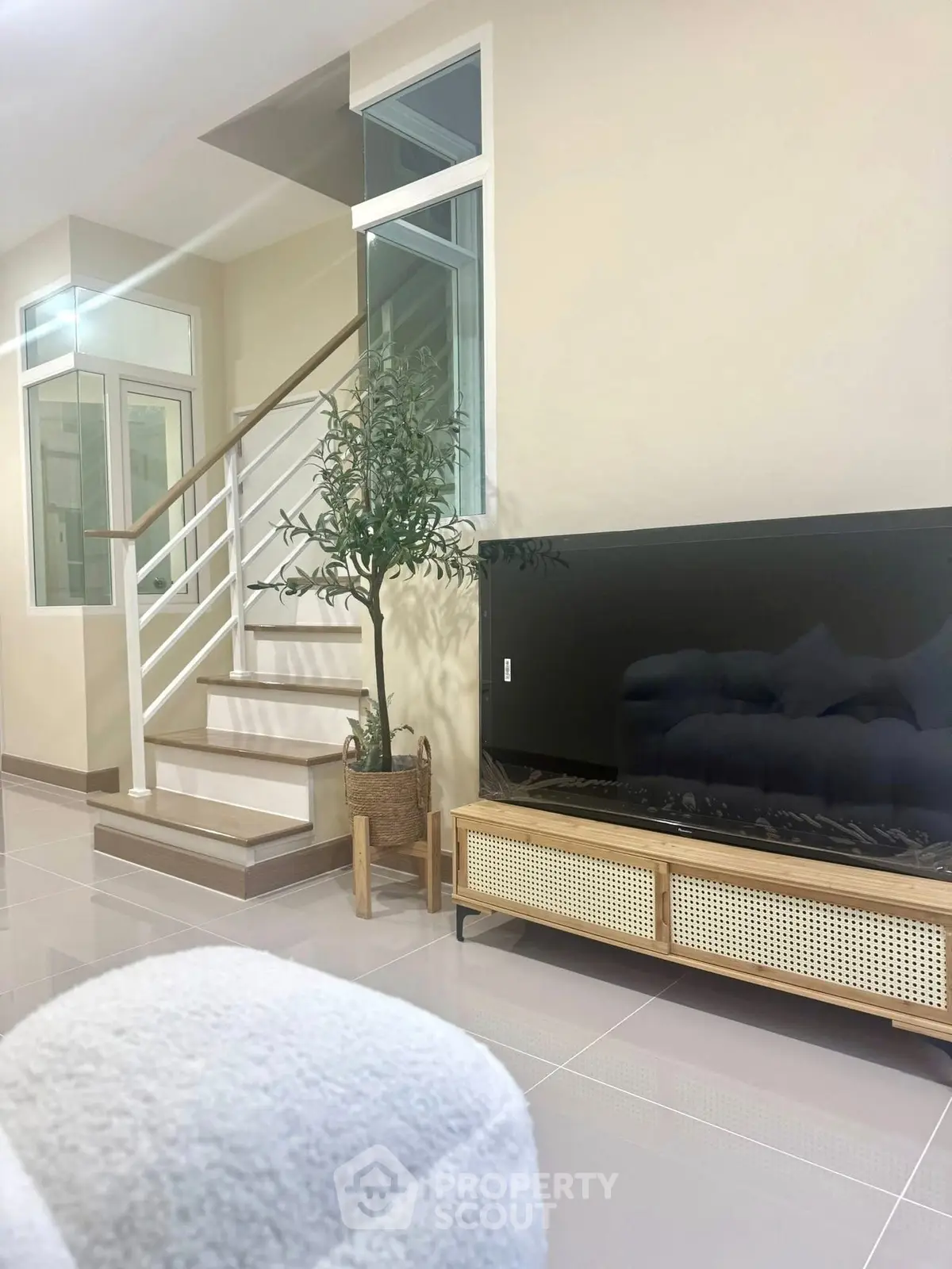 Modern living room with sleek staircase and large TV, perfect for contemporary living.