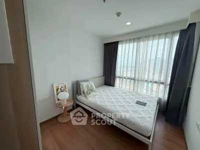 Bright and cozy bedroom with large window and wooden flooring in modern apartment.