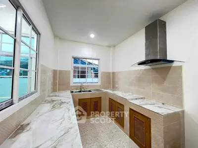 Modern kitchen with marble countertops and sleek ventilation hood