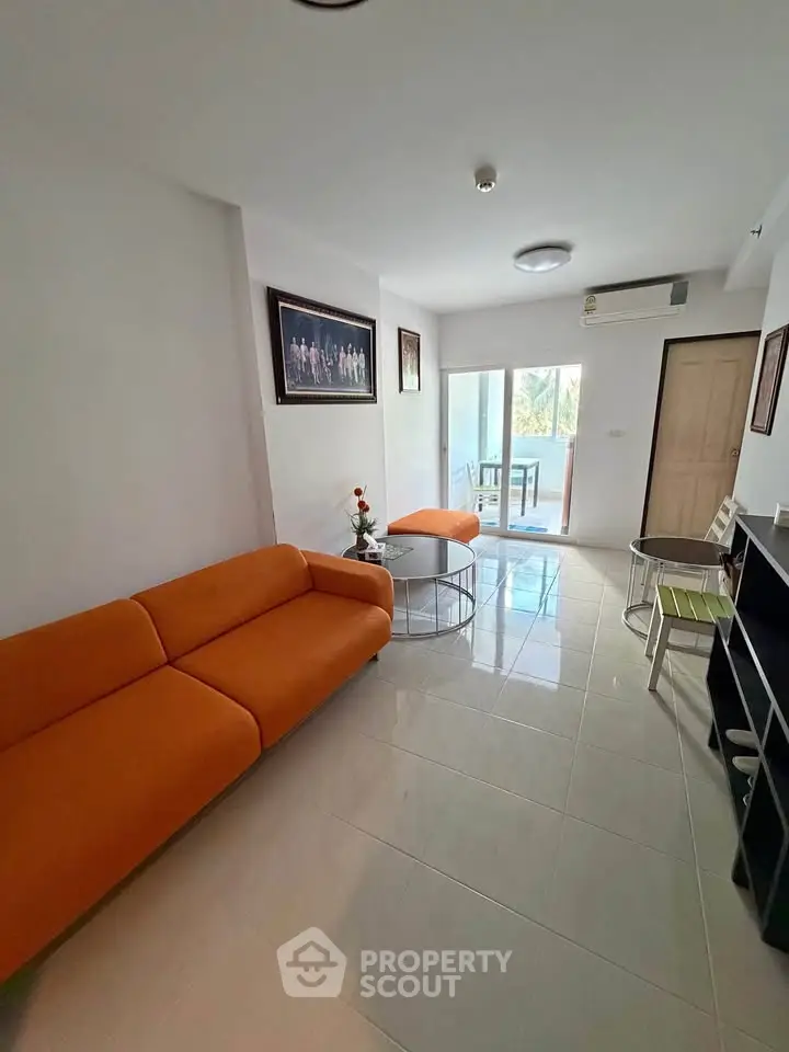 Modern living room with orange sofas and balcony view in a stylish apartment.