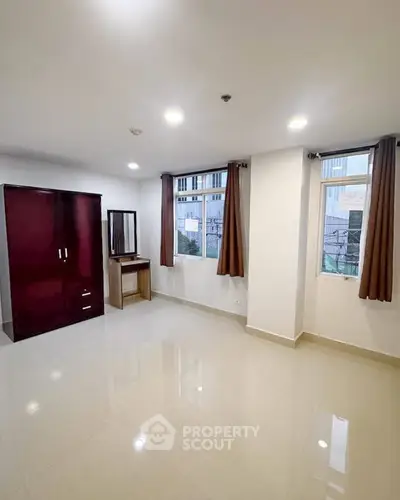 Spacious bedroom with large windows and modern wardrobe in a bright apartment.
