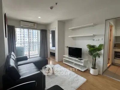 Modern living room with sleek black sofa, TV, and balcony view in a stylish apartment.
