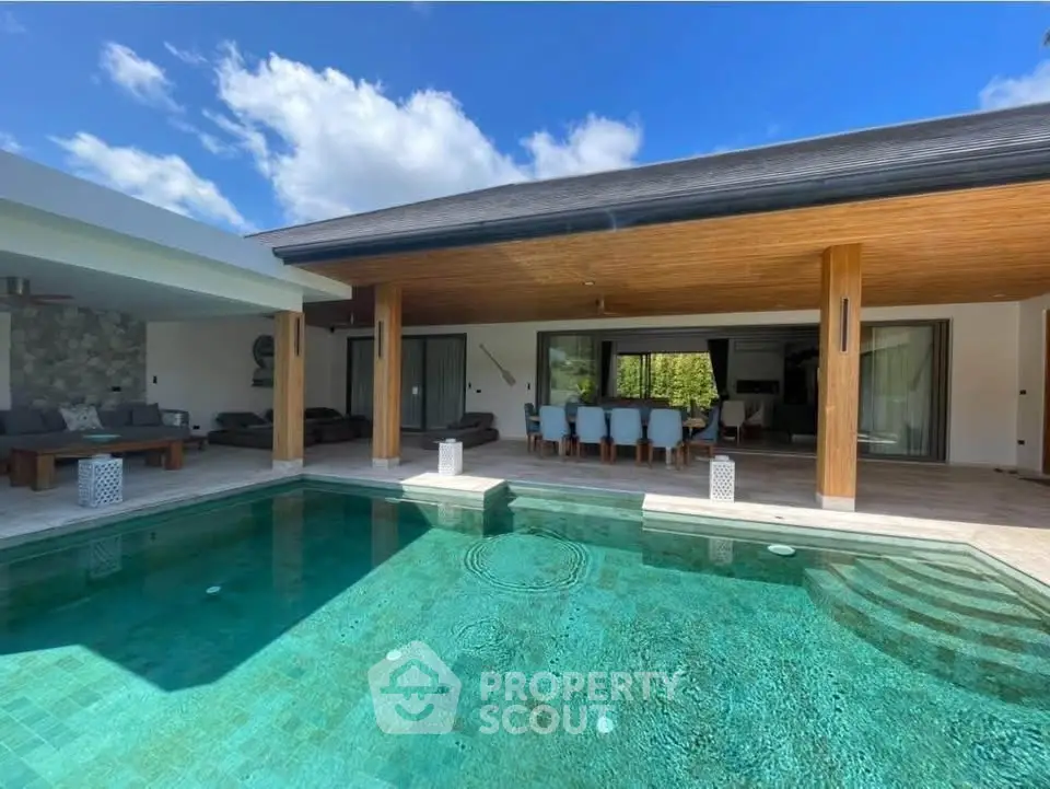 Luxurious villa with stunning pool and spacious outdoor seating area under a wooden ceiling.