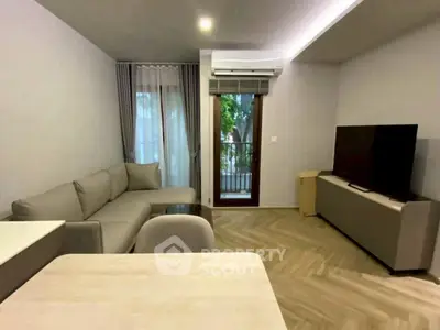 Modern living room with sleek furniture and large TV, featuring a small balcony view.
