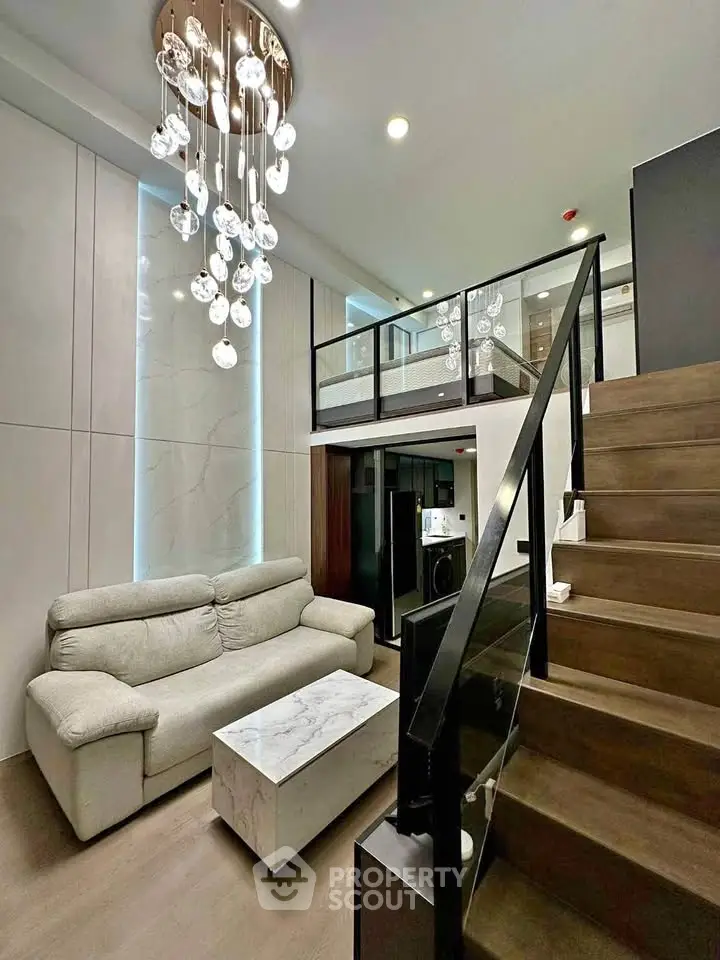 Modern loft-style living room with elegant chandelier and stylish staircase
