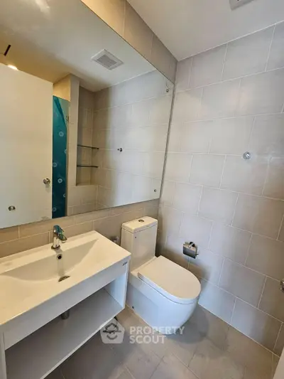 Modern bathroom with sleek fixtures and large mirror in contemporary apartment.