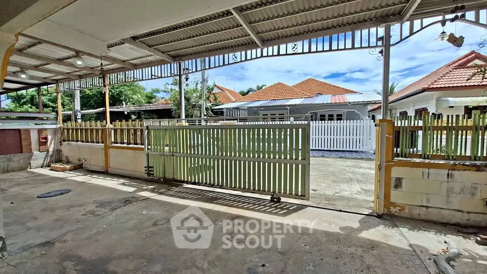 Spacious outdoor area with gated entrance and view of charming houses.