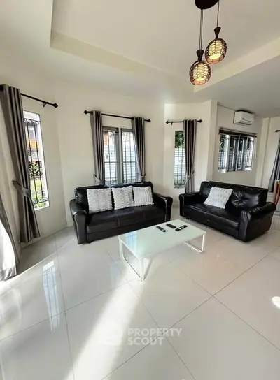 Spacious living room with modern black leather sofas and elegant lighting, perfect for relaxation and entertaining.