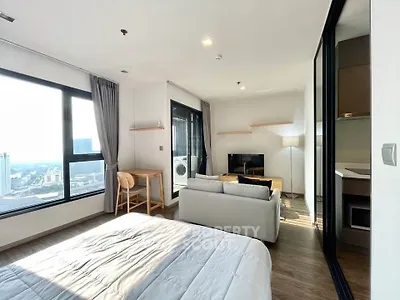 Modern studio apartment with panoramic city view, featuring cozy living area and sleek kitchen design.