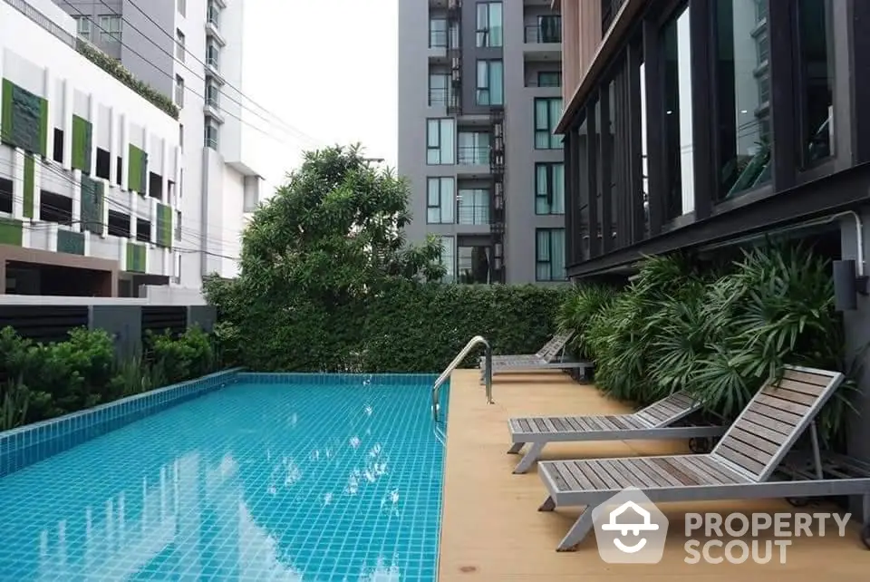 Modern apartment building with a luxurious pool and lush greenery, perfect for relaxation and leisure.