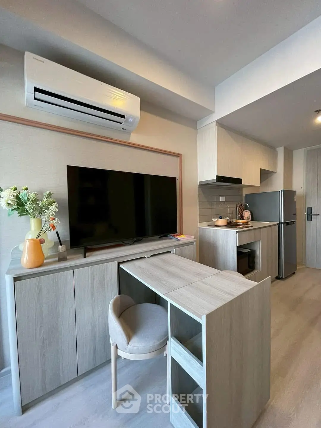 Modern compact living room with integrated kitchen, featuring sleek cabinetry and stylish decor.