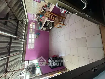 Cozy kitchen with vibrant purple walls and tiled flooring, featuring a compact layout and essential appliances.