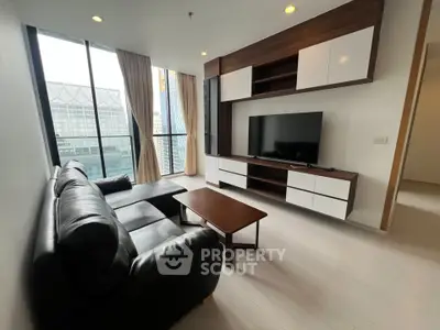 Modern living room with large windows and sleek furniture in a high-rise apartment.