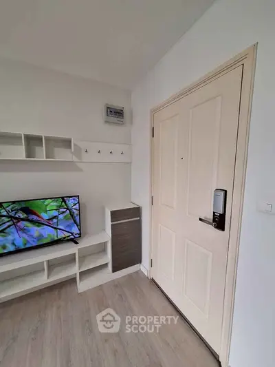 Modern apartment entrance with digital lock and sleek TV setup.