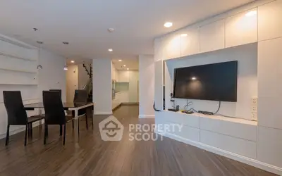 Modern open-plan living room with sleek TV setup and dining area.