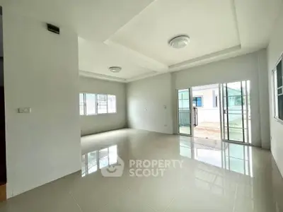 Spacious modern living room with large windows and sliding glass doors opening to a balcony.