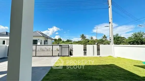 Spacious backyard with lush green lawn and modern fence in a serene neighborhood.