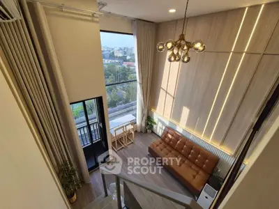 Stunning loft-style living room with high ceilings and city view balcony, perfect for modern urban living.