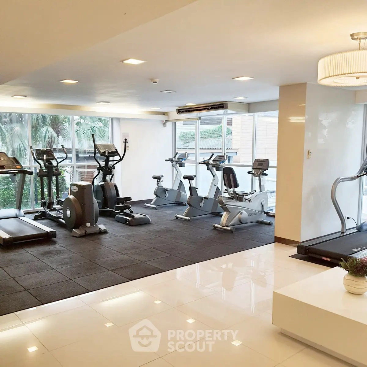 Modern gym with state-of-the-art equipment and large windows in luxury apartment building.