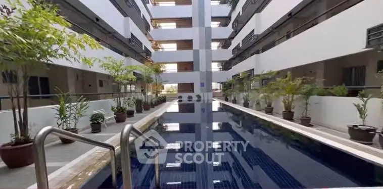 Modern apartment complex with sleek pool and lush greenery, offering a serene and luxurious living experience.