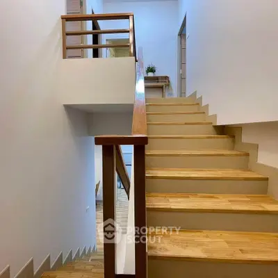 Elegant wooden staircase with modern railing in a bright home interior.