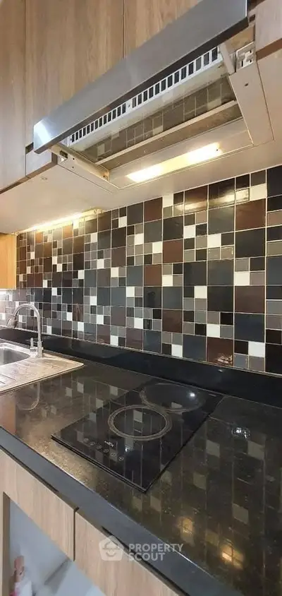 Modern kitchen with sleek black countertop and stylish tile backsplash