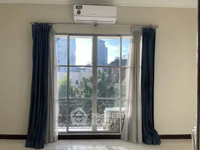 Bright room with large window and city view, featuring elegant curtains and air conditioning.