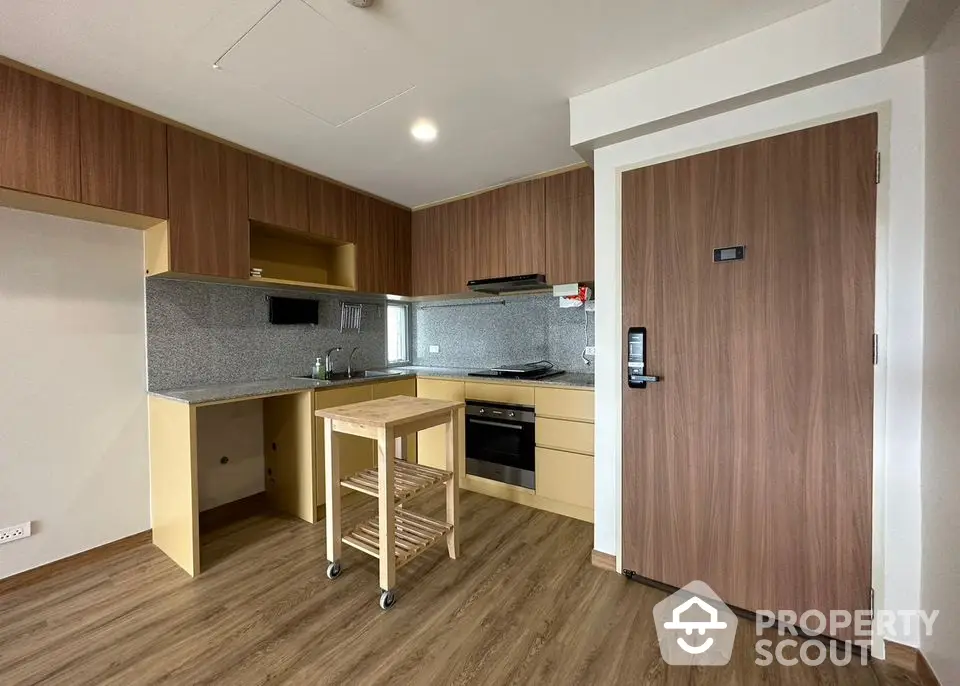 Modern kitchen with wooden cabinetry and compact island in stylish apartment