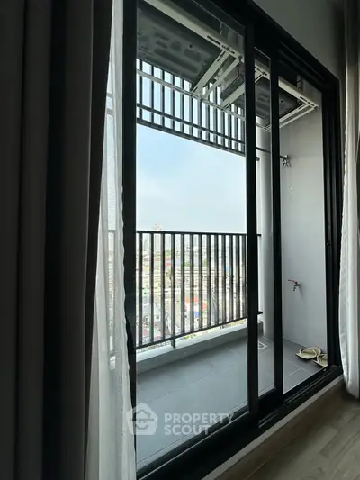 Modern apartment balcony with city view and sliding glass doors, perfect for urban living.