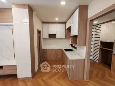 Modern kitchen with sleek cabinetry and herringbone wood flooring